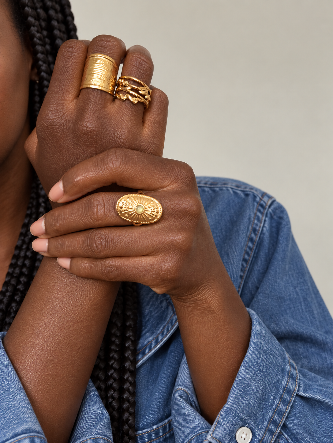 Bijoux dorés portés sur une peau et un vêtement aux tons naturels